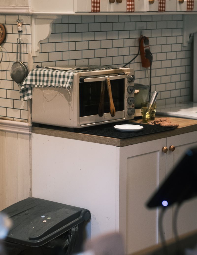 Cozy kitchen corner featuring a countertop toaster oven with cooking utensils and rustic decor in a small space