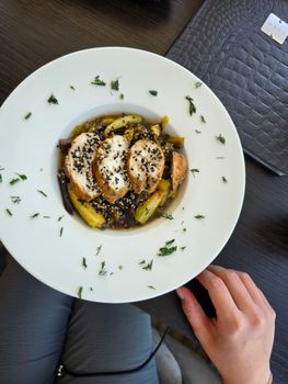Grilled chicken served with sauteed zucchini and sesame seeds, garnished with herbs.