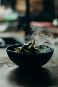 Close-up of steaming edamame beans in a dark bowl, showcasing a delicious healthy snack.