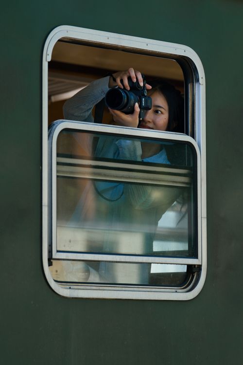 Free Woman taking photos through a train window, capturing picturesque scenery. Stock Photo