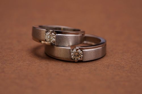 Free Close-up of two elegant diamond wedding rings on a textured brown surface, symbolizing love and commitment. Stock Photo