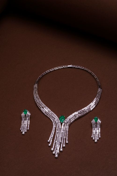 Free Luxurious diamond and emerald necklace and earrings set elegantly displayed on a brown surface. Stock Photo