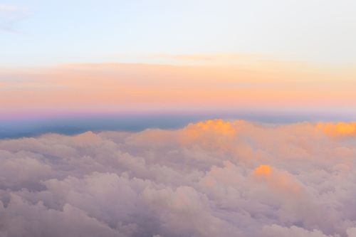 Free Serene view of fluffy clouds at sunset with warm pastel colors and soft gradient sky. Stock Photo