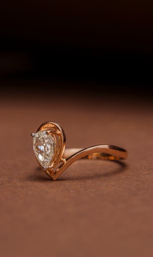 Free Stylish gold engagement ring featuring a heart-shaped diamond on a brown background. Stock Photo