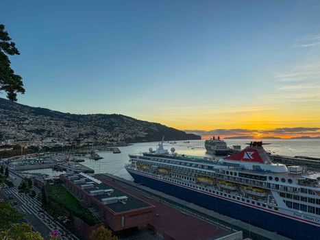 Scenic view of cruise ships docked in Funchal, Madeira during sunset, showcasing coastal beauty.