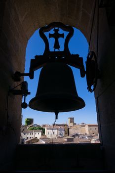 Silhouette of a bell tower overlooking the historic cityscape of Cáceres, Spain.