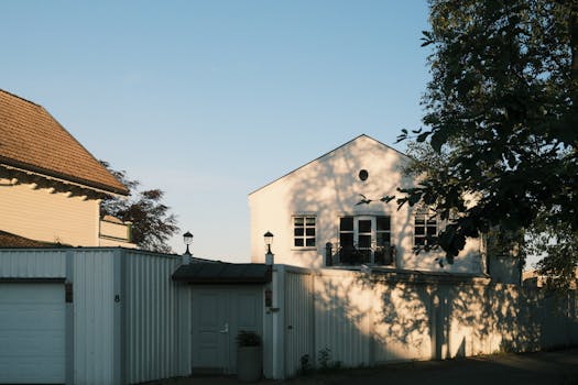 A charming white house with a garden, bathed in warm evening light.