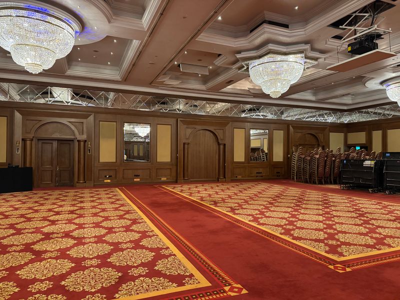Spacious banquet hall with luxurious chandeliers and red carpet flooring