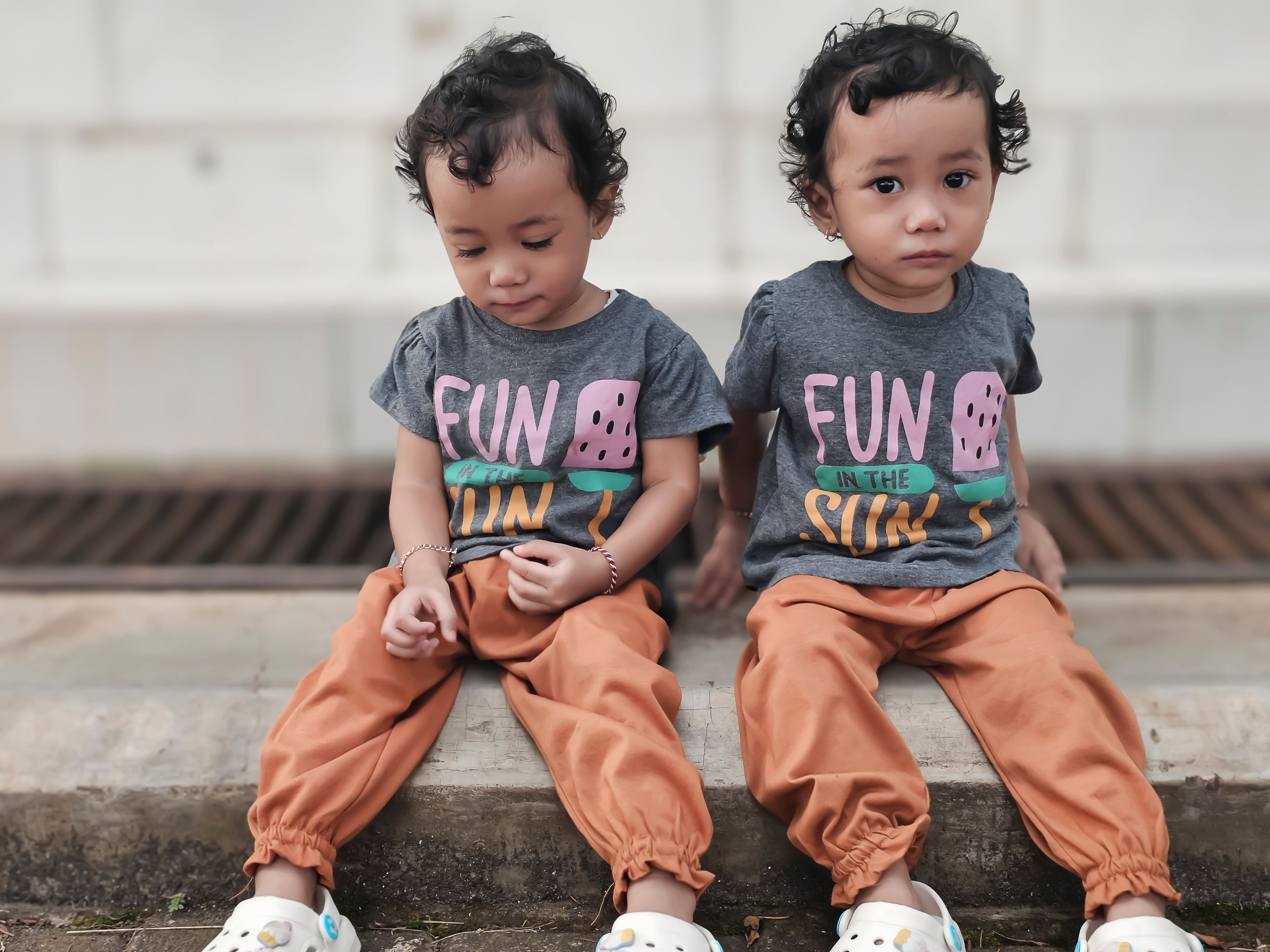 Playful Twins in Matching Outfits Outdoors · Free Stock Photo