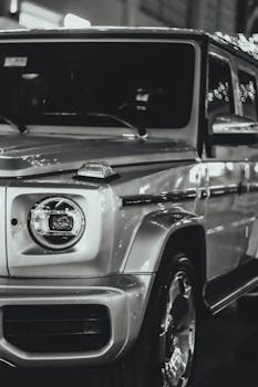 Elegant black and white photo of a luxury SUV under city lights, emphasizing style.