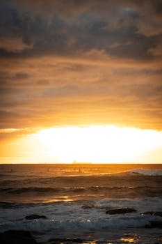 Stunning sunrise over the ocean at Sunshine Coast, Queensland with surfers silhouetted against the golden sky.