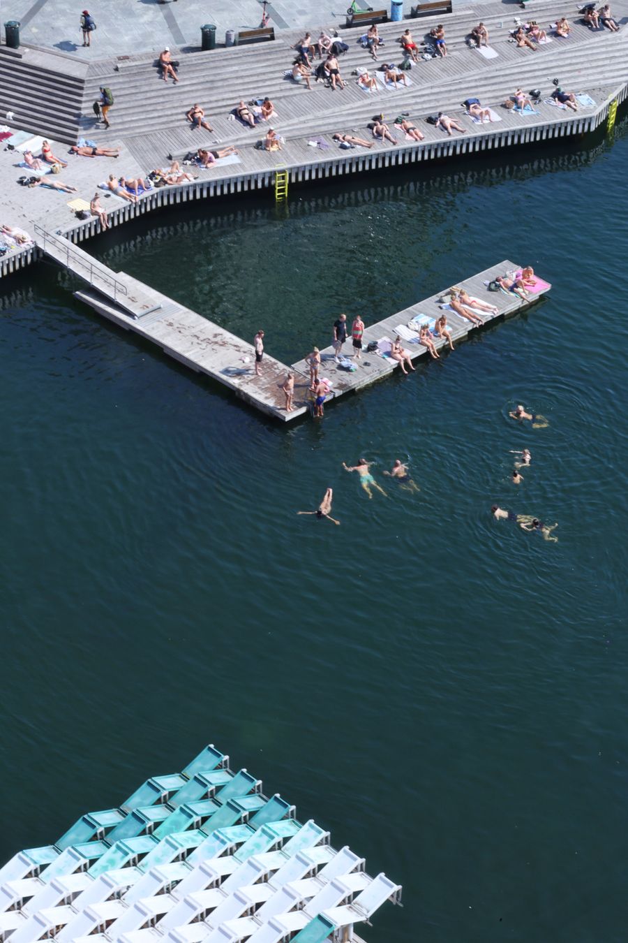 Swimmers and sunbathers along a city harbour promenade — photo by Jess Chen on Pexels