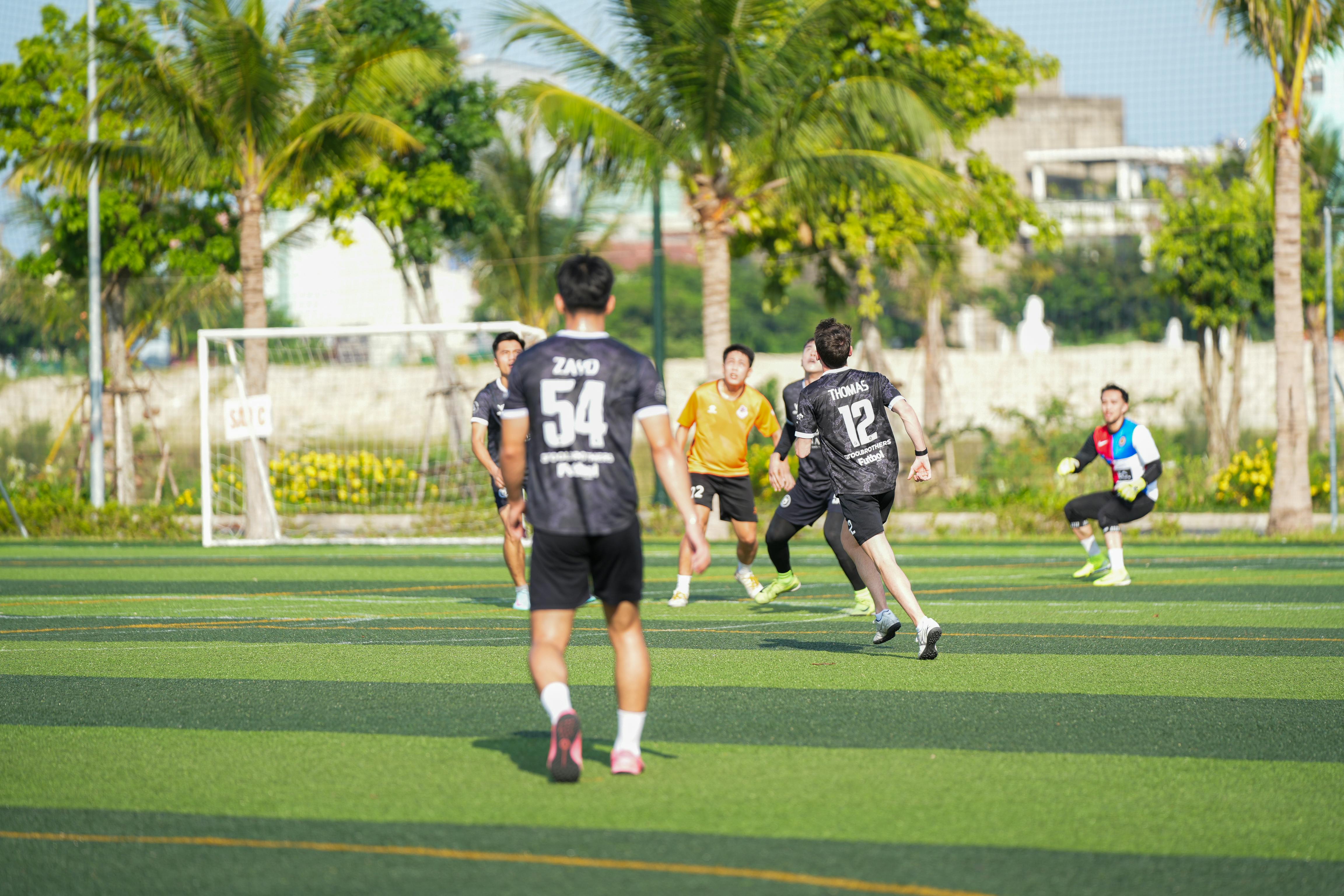 A group of young adults playing an energetic soccer match outdoors on a sunny day.