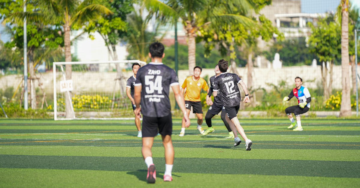 A group of young adults playing an energetic soccer match outdoors on a sunny day.