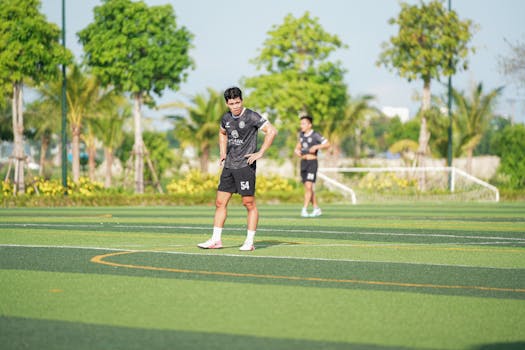 A young athlete stands confidently on a sunny outdoor soccer field.