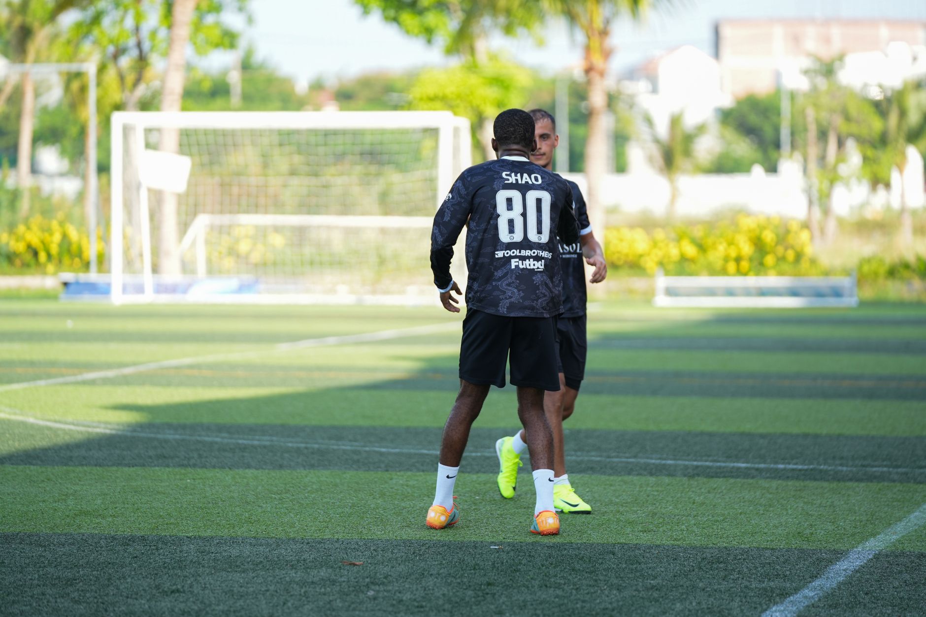 Two men participating in an outdoor soccer training session on a sunny day, practicing ball skills.