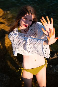 Confident woman enjoying the sunset in a trendy crochet sweater and green bikini.