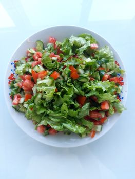 Colorful salad featuring lettuce, cucumber, and tomatoes on a decorative plate.