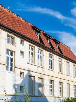 Charming European-style building with classic architecture and vibrant red roof under a clear blue sky.