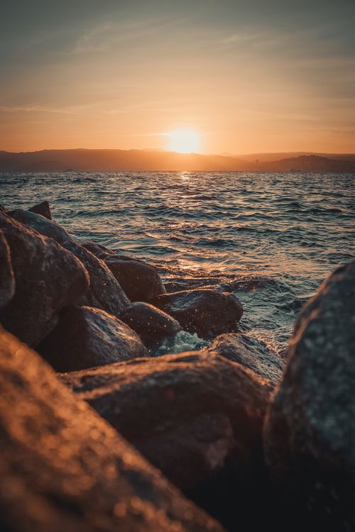 Free Breathtaking view of sunset over the ocean with rocky foreground, capturing the beauty of nature. Stock Photo
