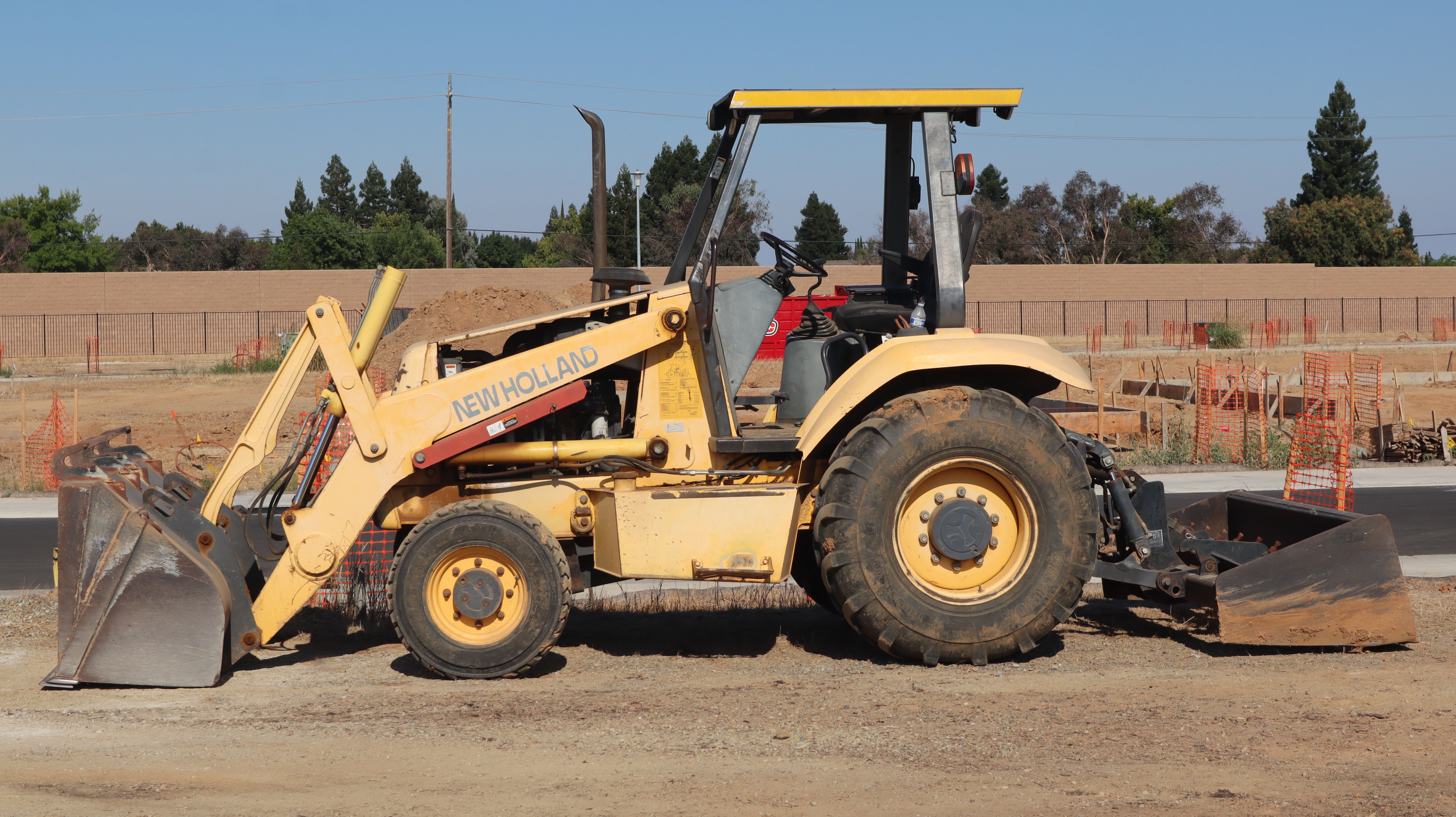 Yellow New Holland backhoe at a construction site in Elk Grove, California.