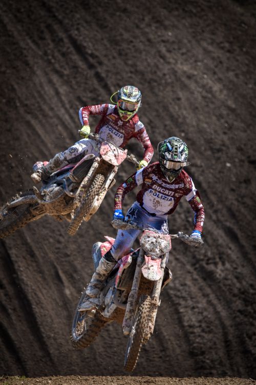 Free Dynamic shot of two motocross riders jumping together on a dirt track. Stock Photo