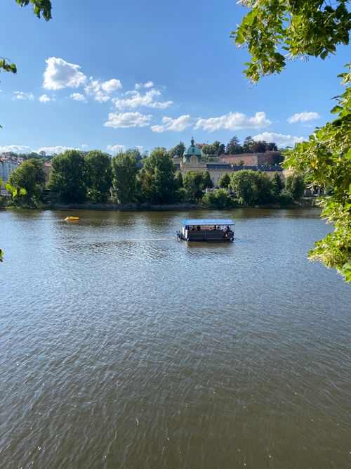 Free Boat cruising on a serene river under a clear blue sky. Stock Photo