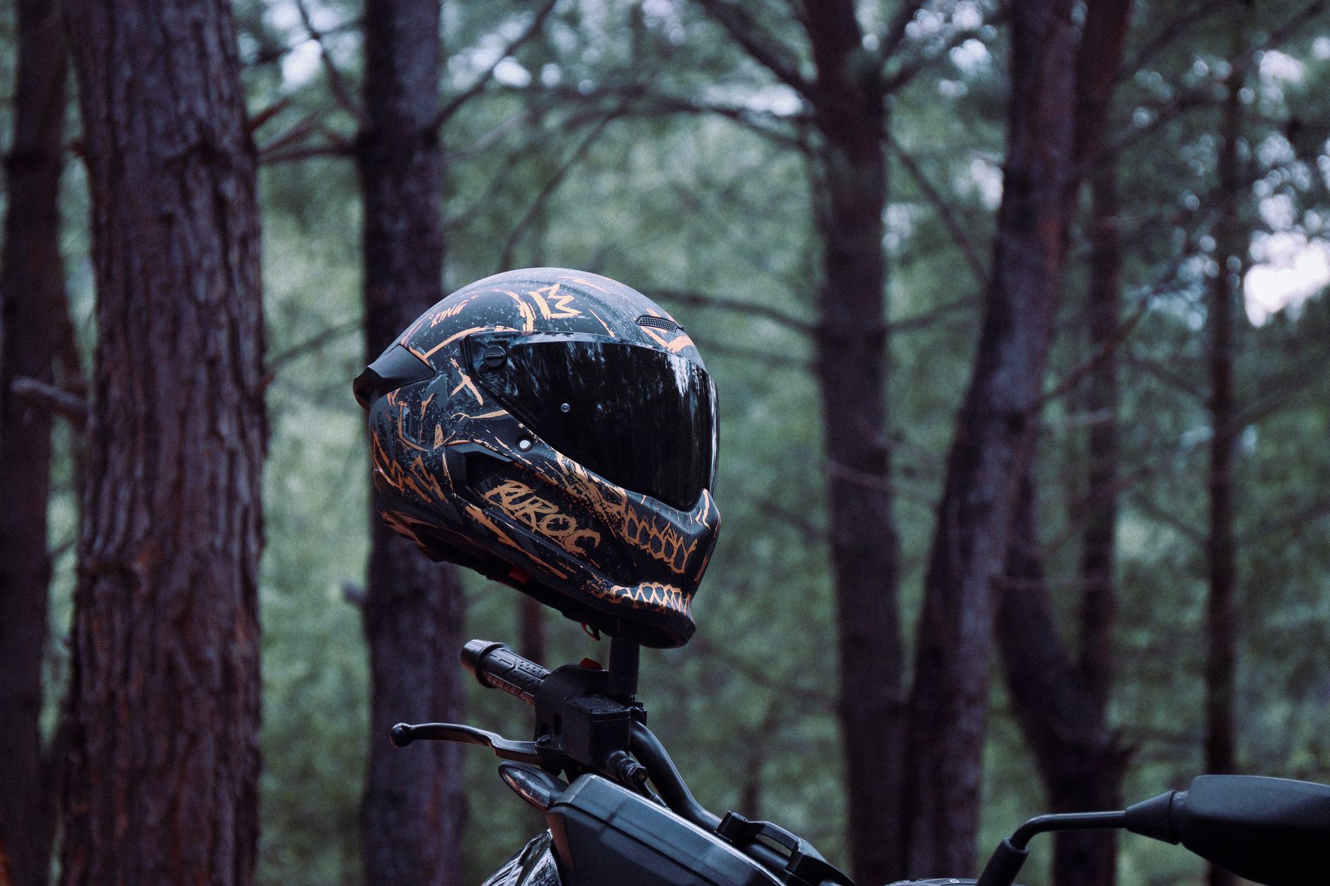 Stylish motorcycle helmet on bike amidst serene forest backdrop in Antalya, Türkiye.