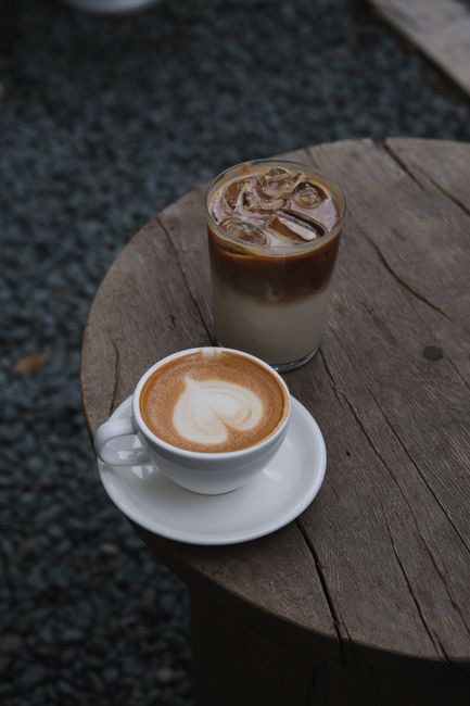 Cozy scene of hot latte with latte art and iced coffee on a rustic wooden table.