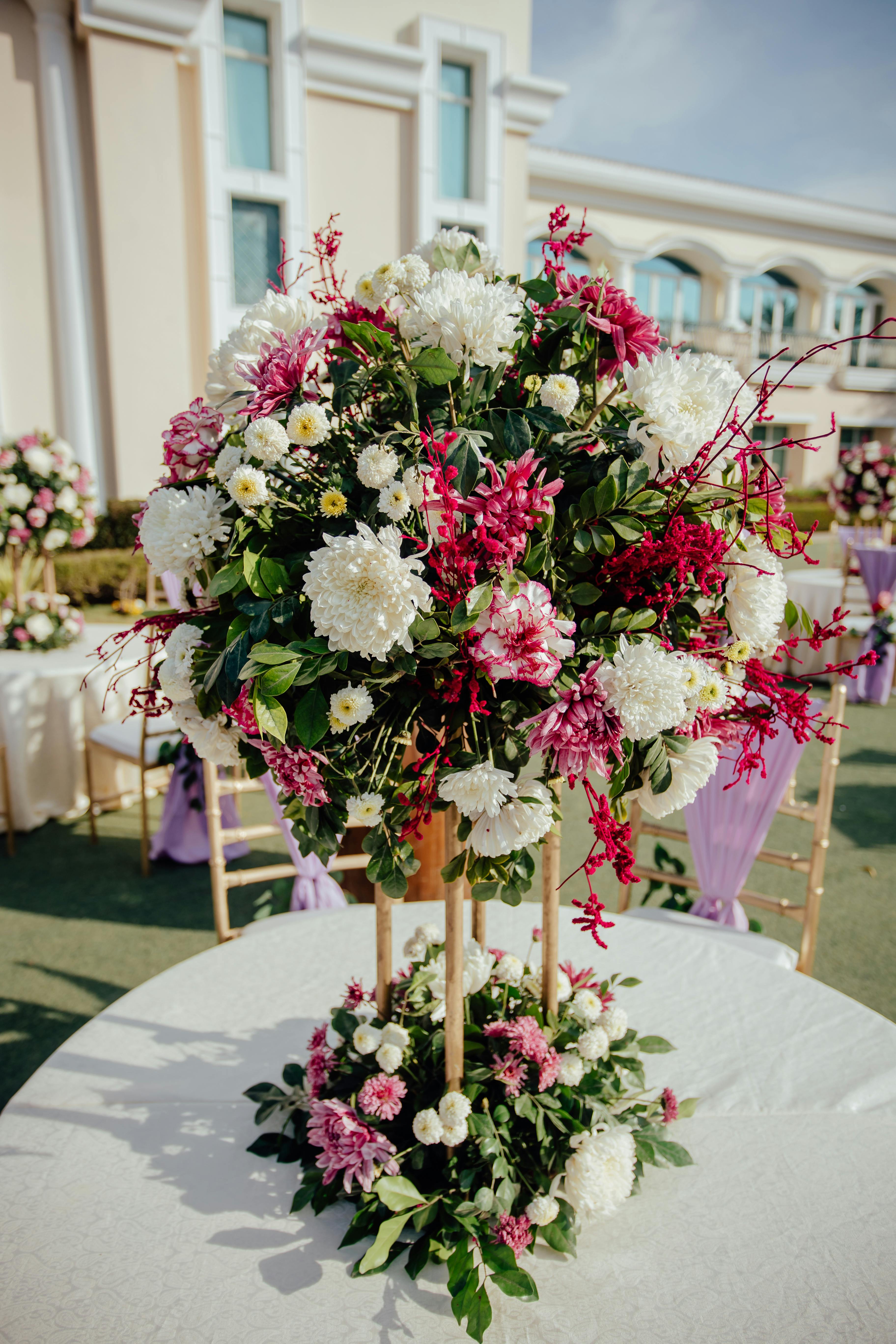 Elegant outdoor floral arrangement with white and pink flowers at a daytime event.