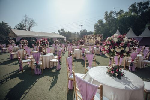 Free Elegant outdoor wedding reception setup with purple and white floral arrangements and tables. Stock Photo