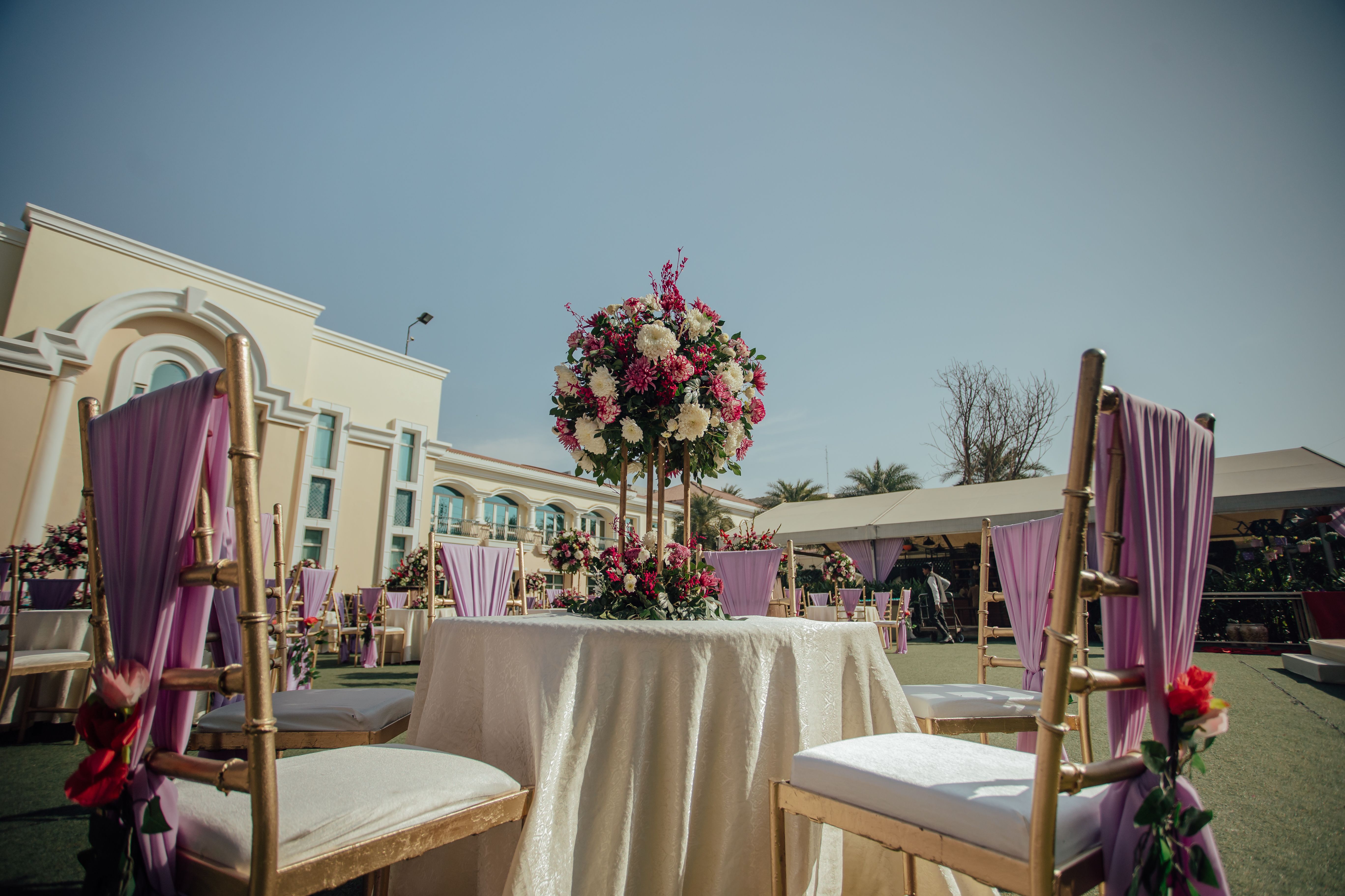 Belle réception de mariage en plein air avec un centre de fleurs et des chaises décorées sous un ciel dégagé.