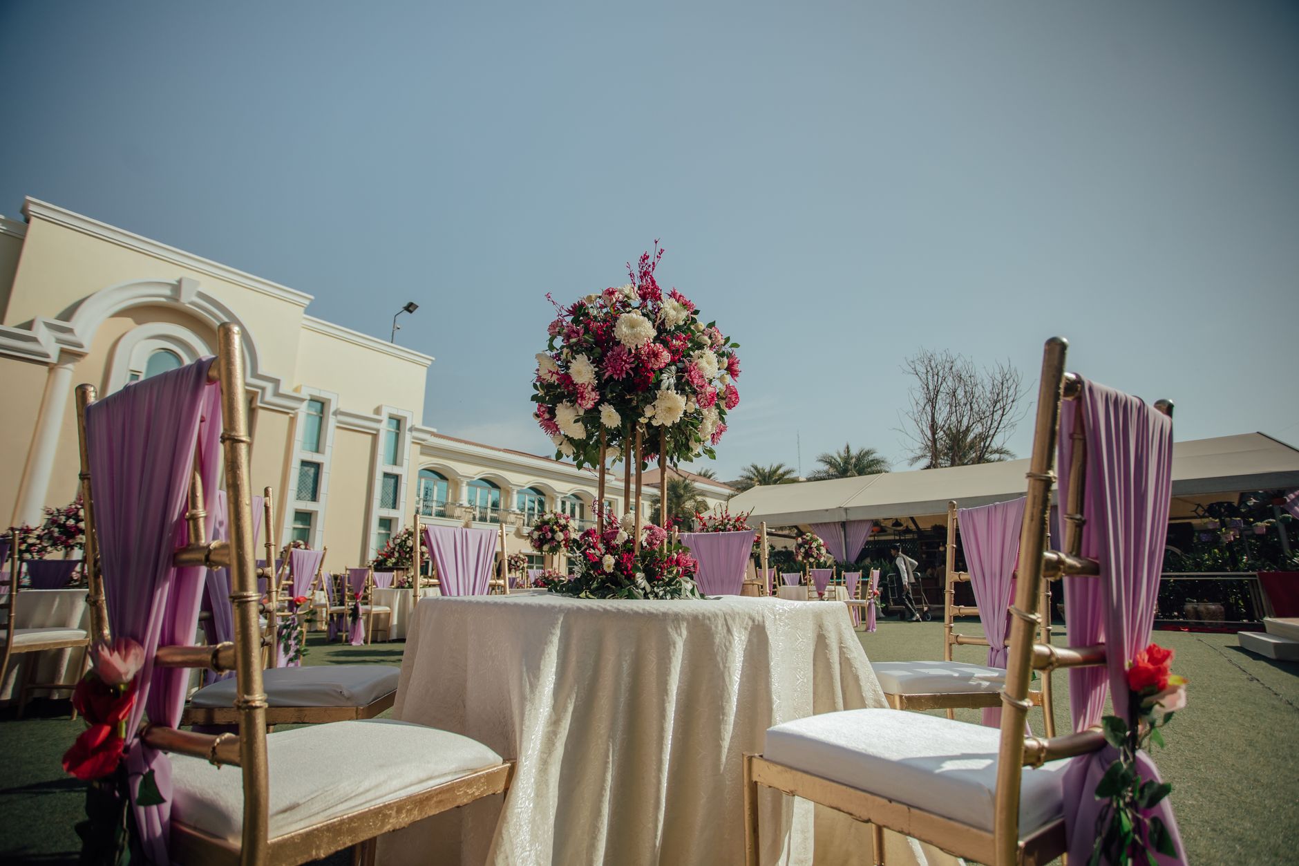 Belle réception de mariage en plein air avec un centre de fleurs et des chaises décorées sous un ciel dégagé.