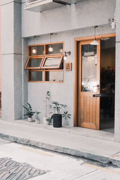 Free Cozy urban cafe entrance with open windows and potted plants on a city street. Stock Photo
