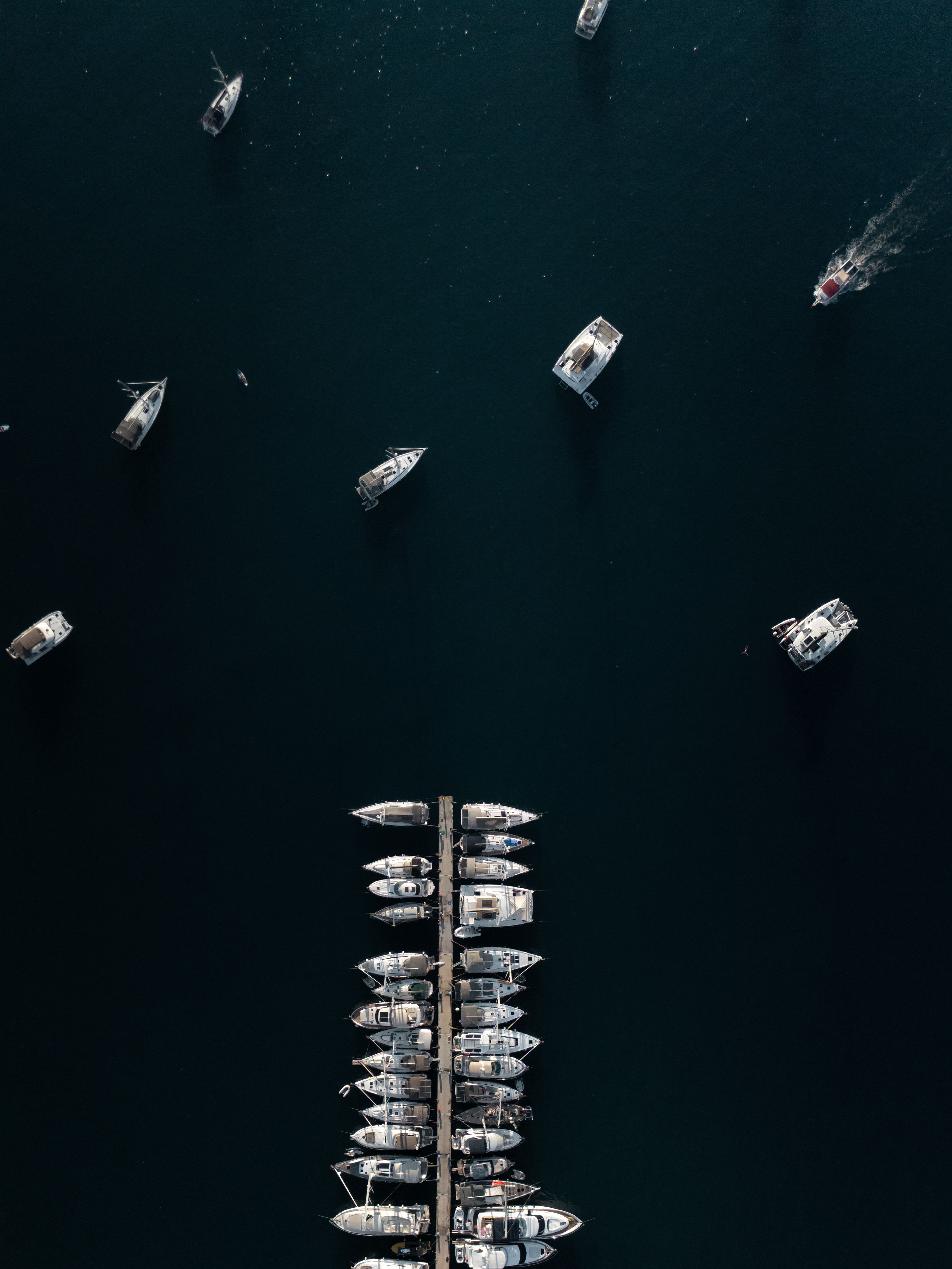 Stunning aerial view of boats docked in a marina surrounded by deep blue water.