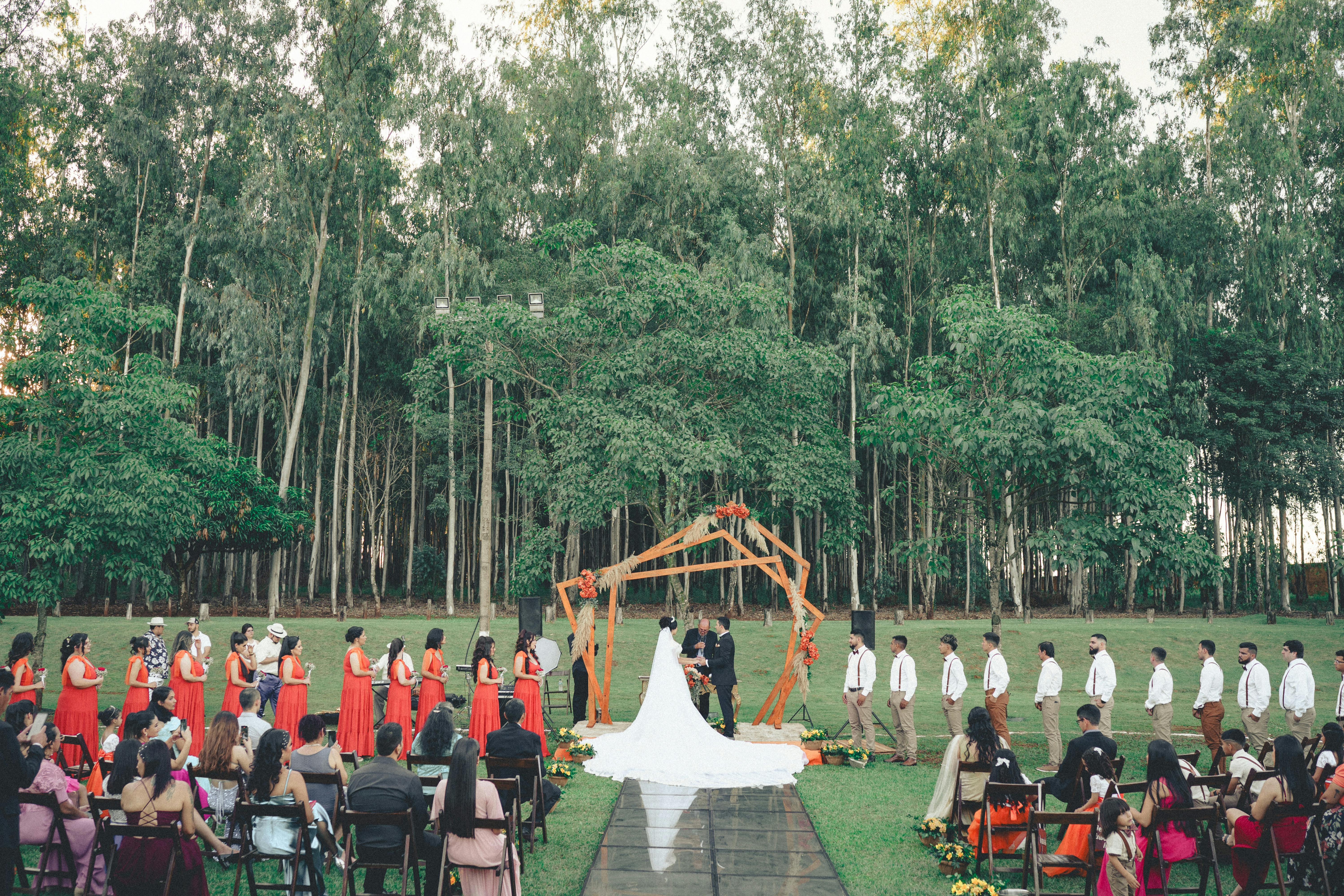 An outdoor wedding aisle lined with guests — phones away, eyes up, the photographer's clean sightline