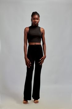 Confident young woman stands in minimalist attire, showcasing modern fashion style.