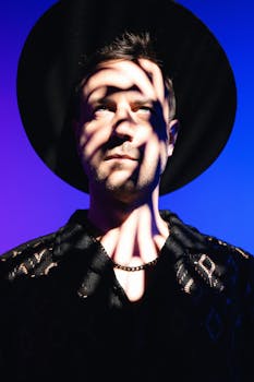 A striking artistic portrait of a man wearing a hat, captured in dramatic lighting with shadow play.