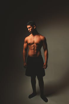 Portrait of a fit young male showcasing his athletic build in dramatic studio lighting.