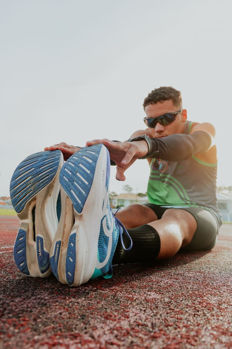 Runner stretching on a sunlit track — photo by Adenir Figueiredo Carvalho on Pexels