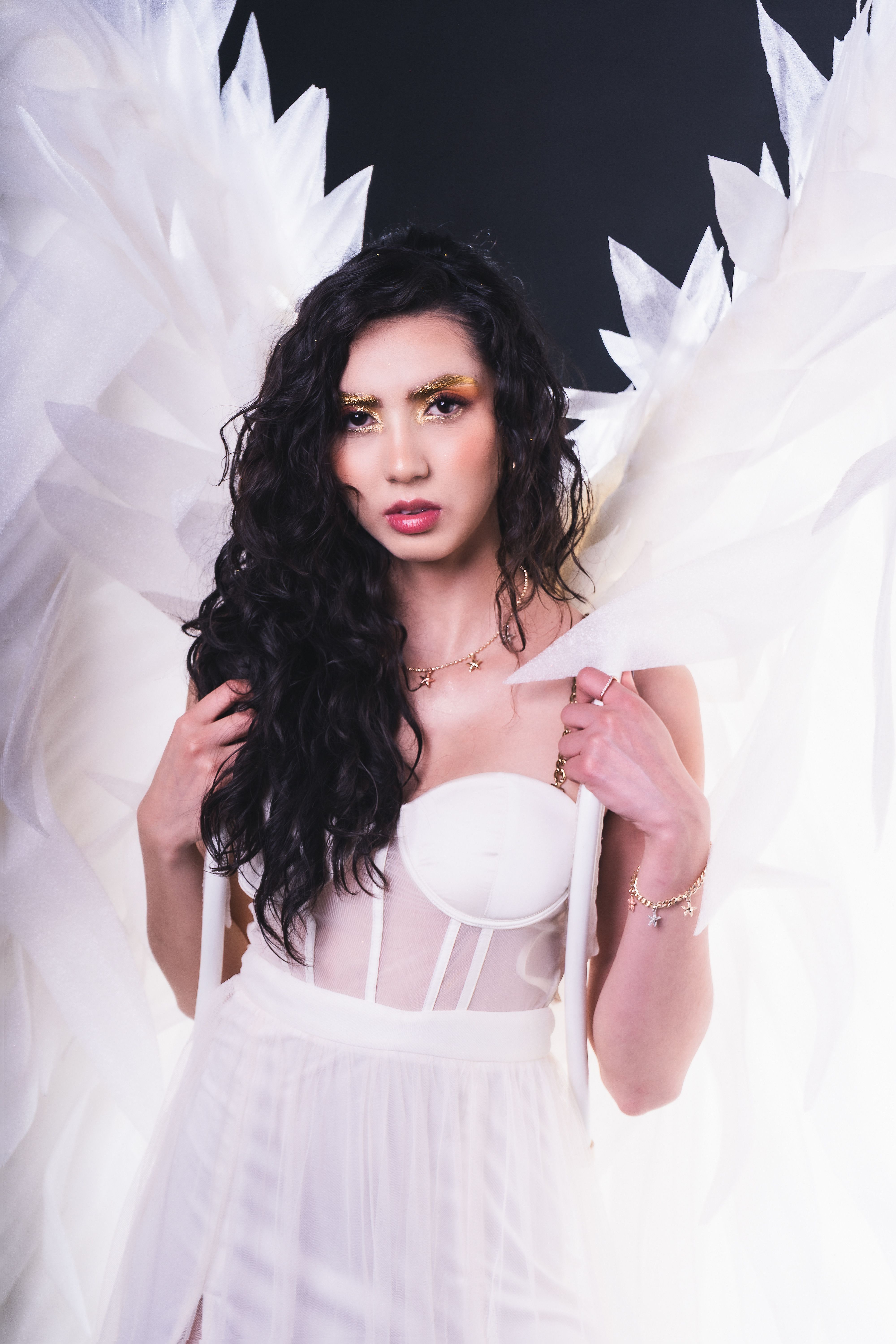 Stylish woman dressed as an angel, showcasing ethereal white wings.