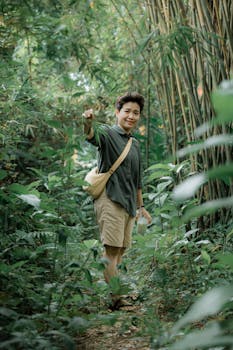 Youth adventurer in casual outfit trekking through a verdant bamboo forest pathway, embracing nature.