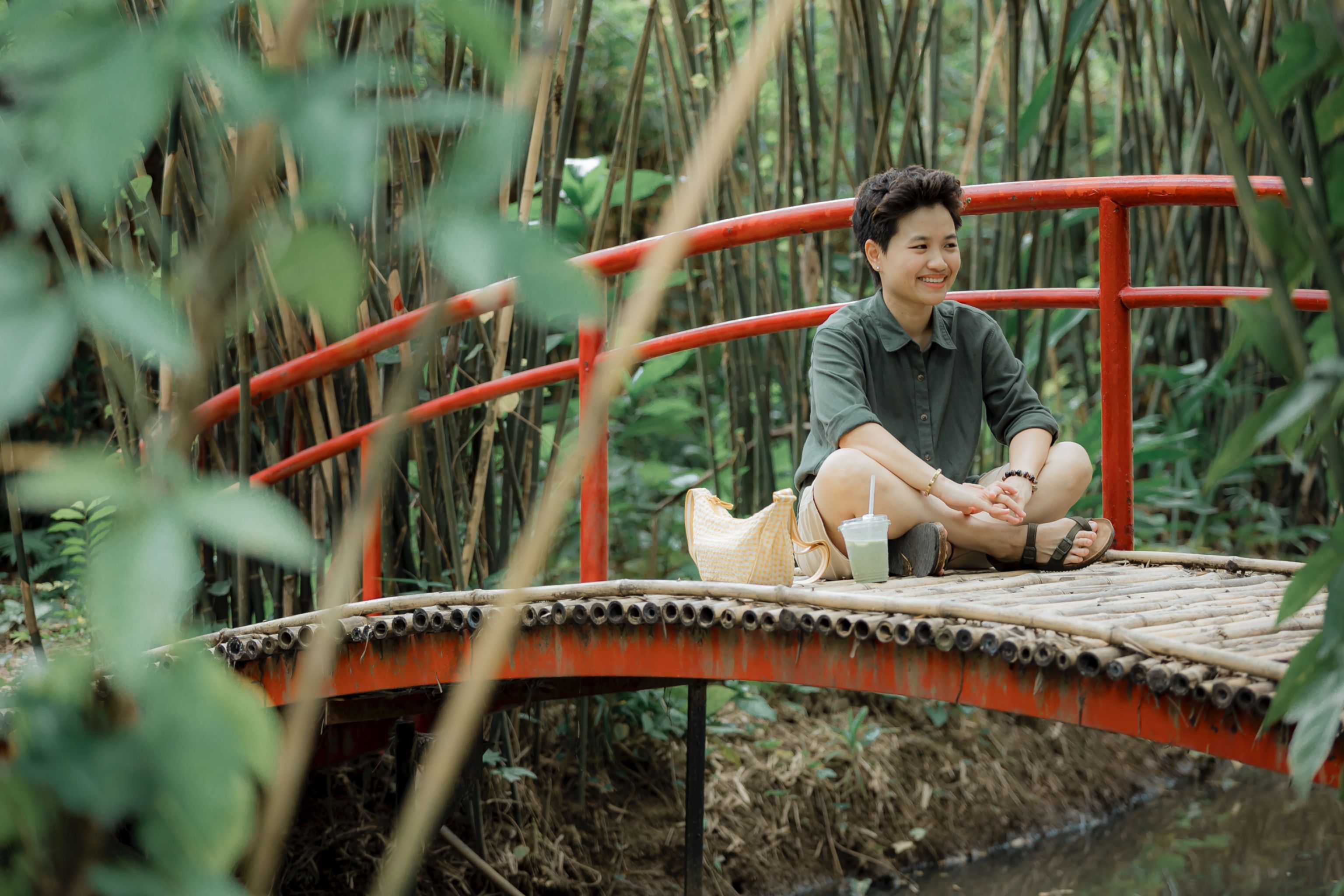 Woman enjoying a peaceful moment on a bamboo bridge surrounded by lush greenery.