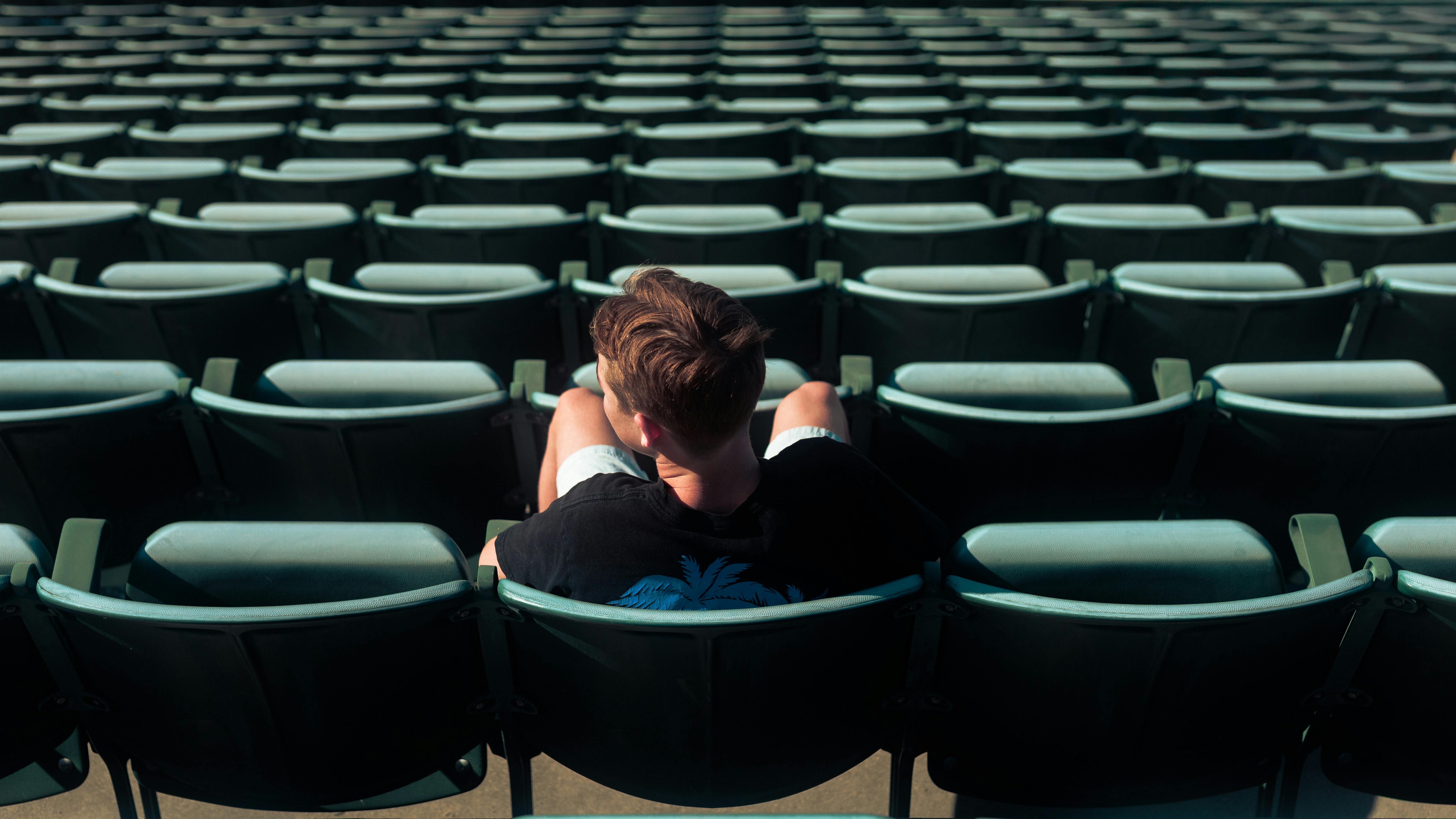 pro athlete sitting alone on a bench in an empty stadium, head down, deep in thought