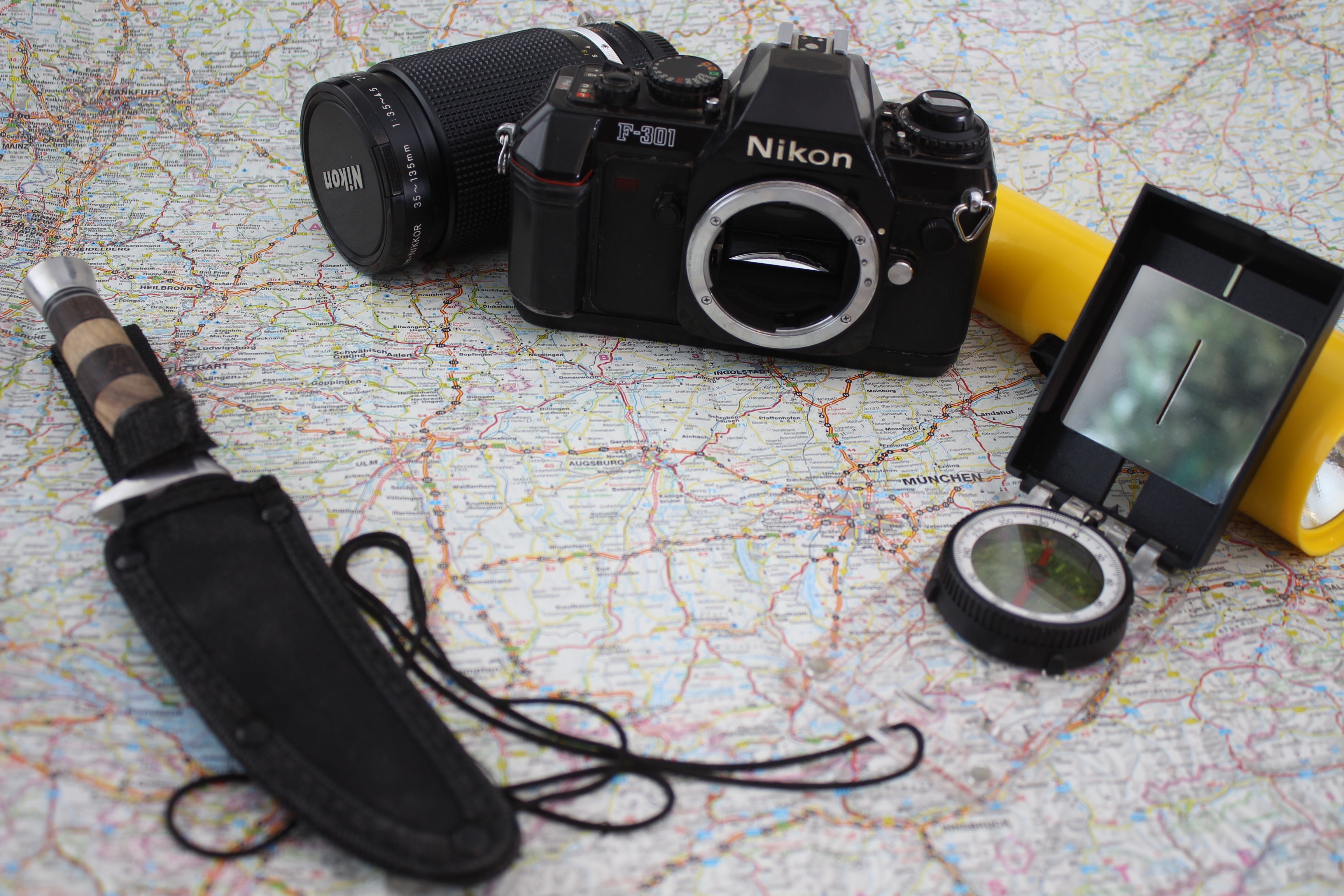 A collection of vintage adventure gear featuring a camera, compass, and knife on a map, ready for exploration.