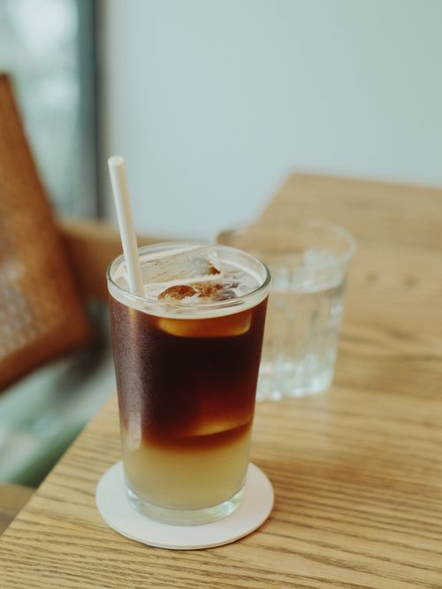 Free Cool iced coffee with lemon on a wooden table, perfect for a refreshing break. Stock Photo