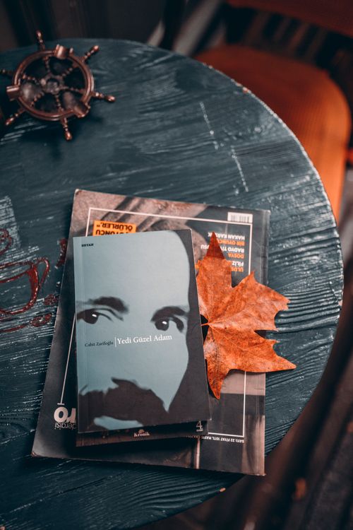Free A cozy autumn scene featuring a book with a maple leaf on a wooden table. Stock Photo