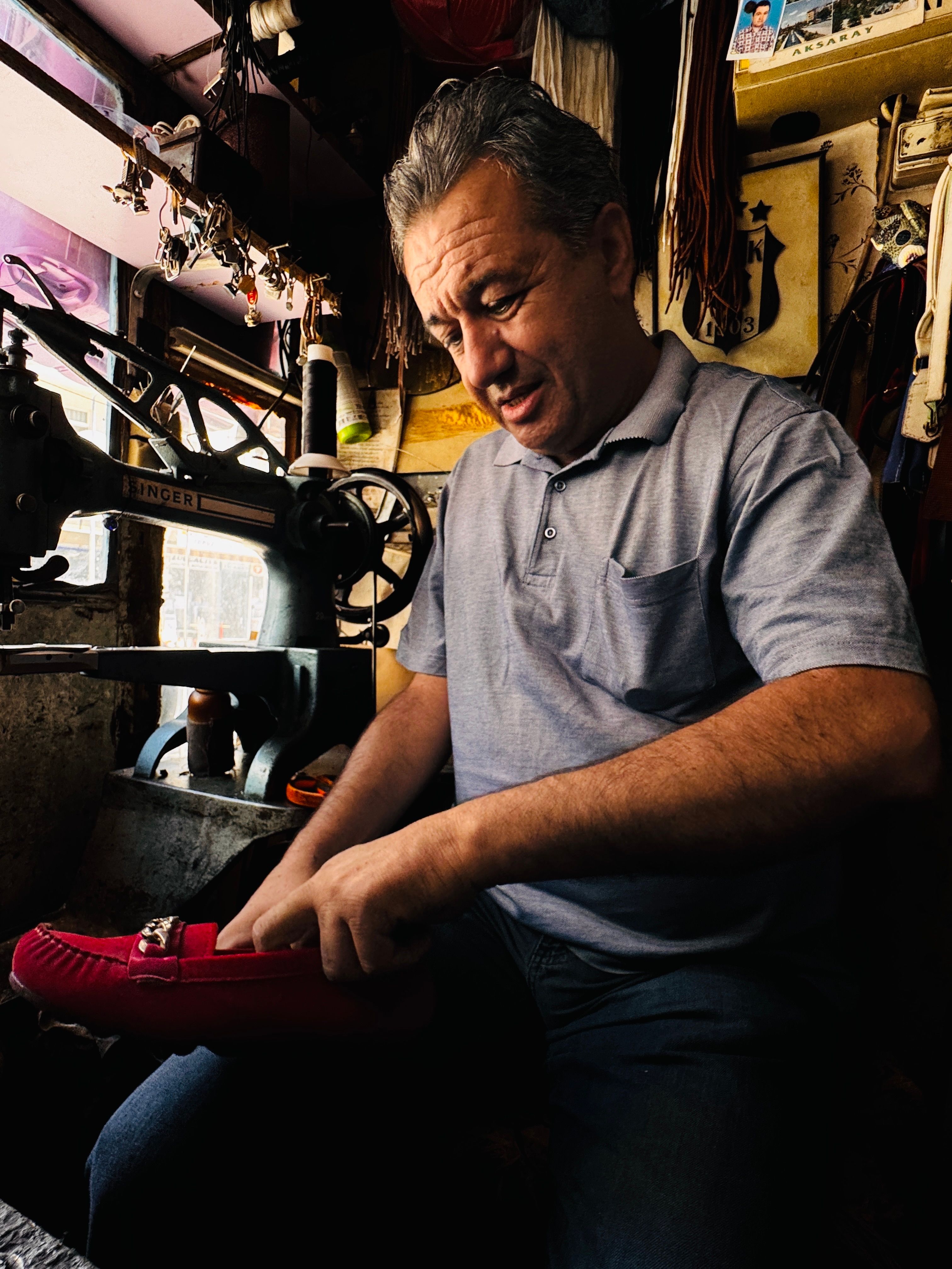 An artisan crafts leather shoes in a traditional workshop with vintage tools.