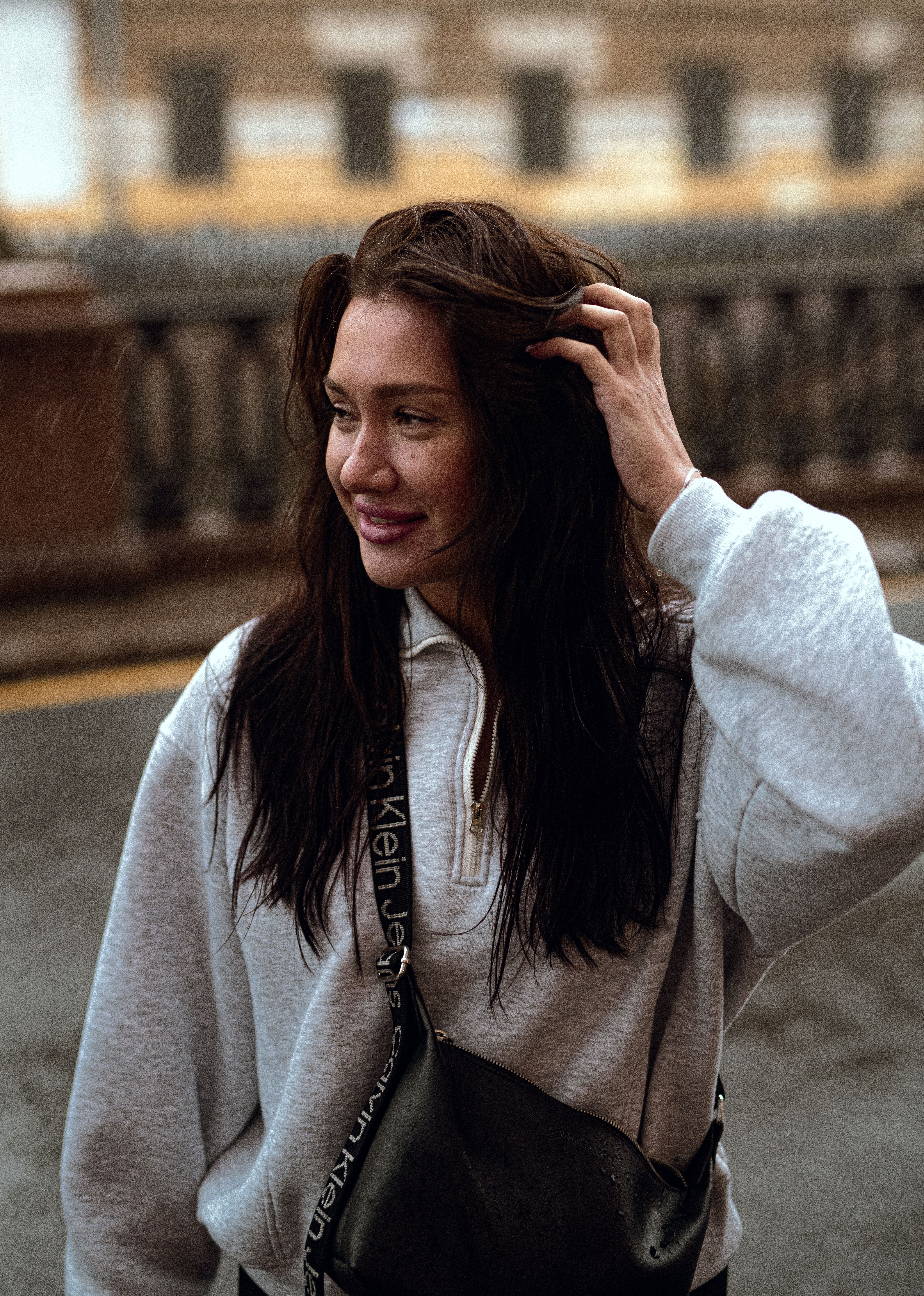 Smiling woman outdoors in casual attire and streetwear on an overcast day.