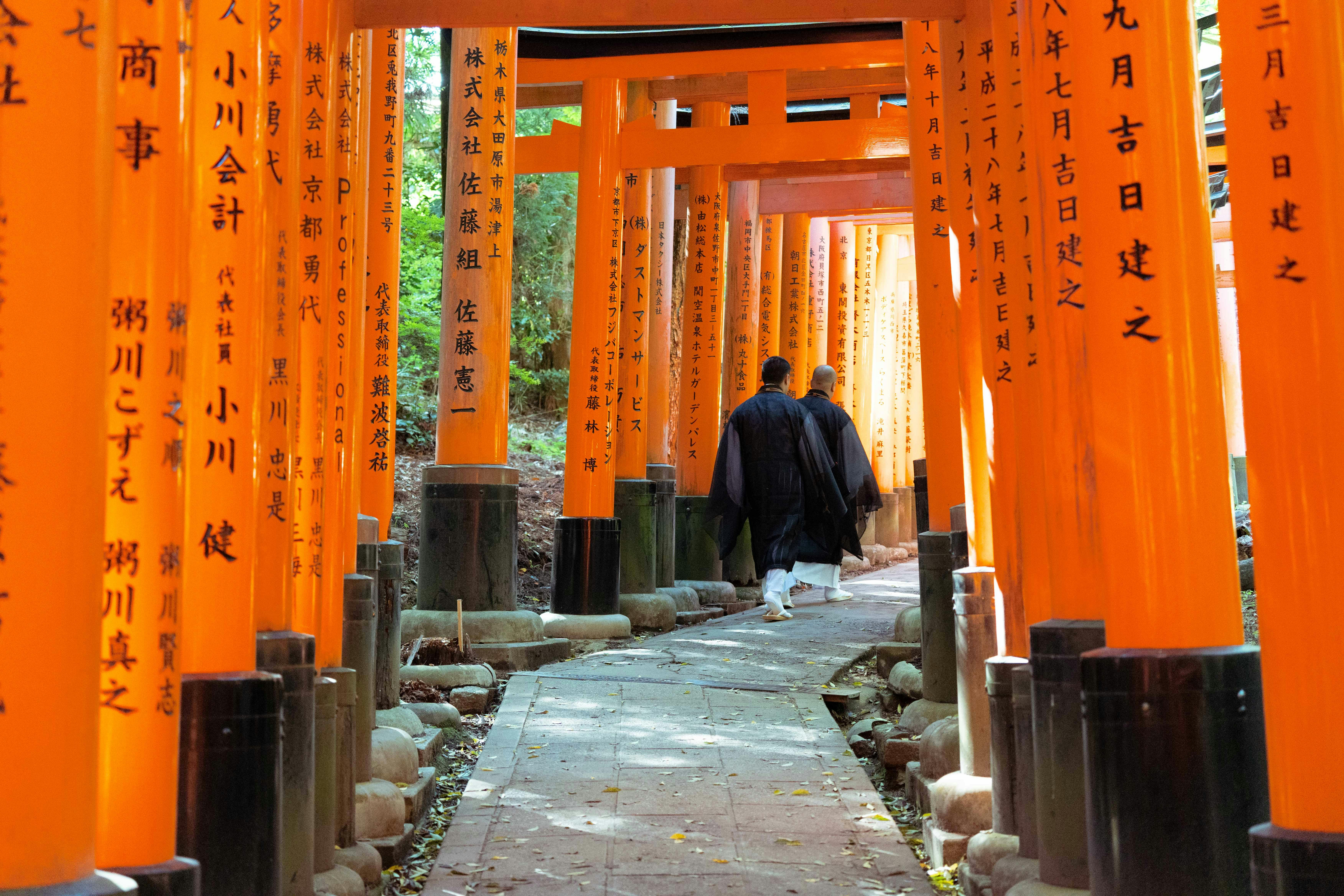 Explore the vibrant torii gates of Fushimi Inari Taisha in Kyoto, Japan with monks.
